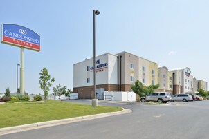A hotel with a prominent sign, a parking lot, and a building with multiple windows.