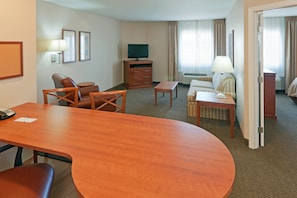 A hotel room with a wooden desk, two chairs, a sofa, a television, and a lamp. - Candlewood Suites Gillette by IHG (Gillette)
