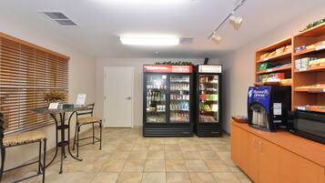 A reception area with a reception desk, two refrigerators stocked with beverages, and a coffee machine.
