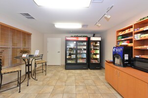 Zona de recepción con mostrador, dos refrigeradores llenos de bebidas y una cafetera.
