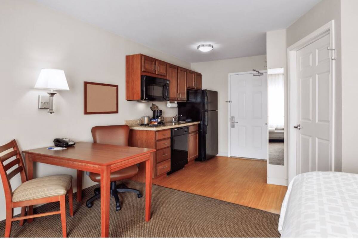Une chambre d’hôtel compacte comprenant un coin cuisine, un espace repas et un lit.