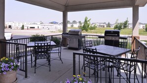 An outdoor patio with a grill, tables, and chairs. - Candlewood Suites Gillette by IHG (Gillette)