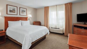 A hotel room with a bed, a desk, a television, and a window with curtains. - Candlewood Suites Gillette by IHG (Gillette)