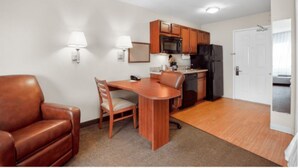 A compact living space with a kitchenette, a dining area with a wooden table and chairs, and a leather sofa. - Candlewood Suites Gillette by IHG (Gillette)