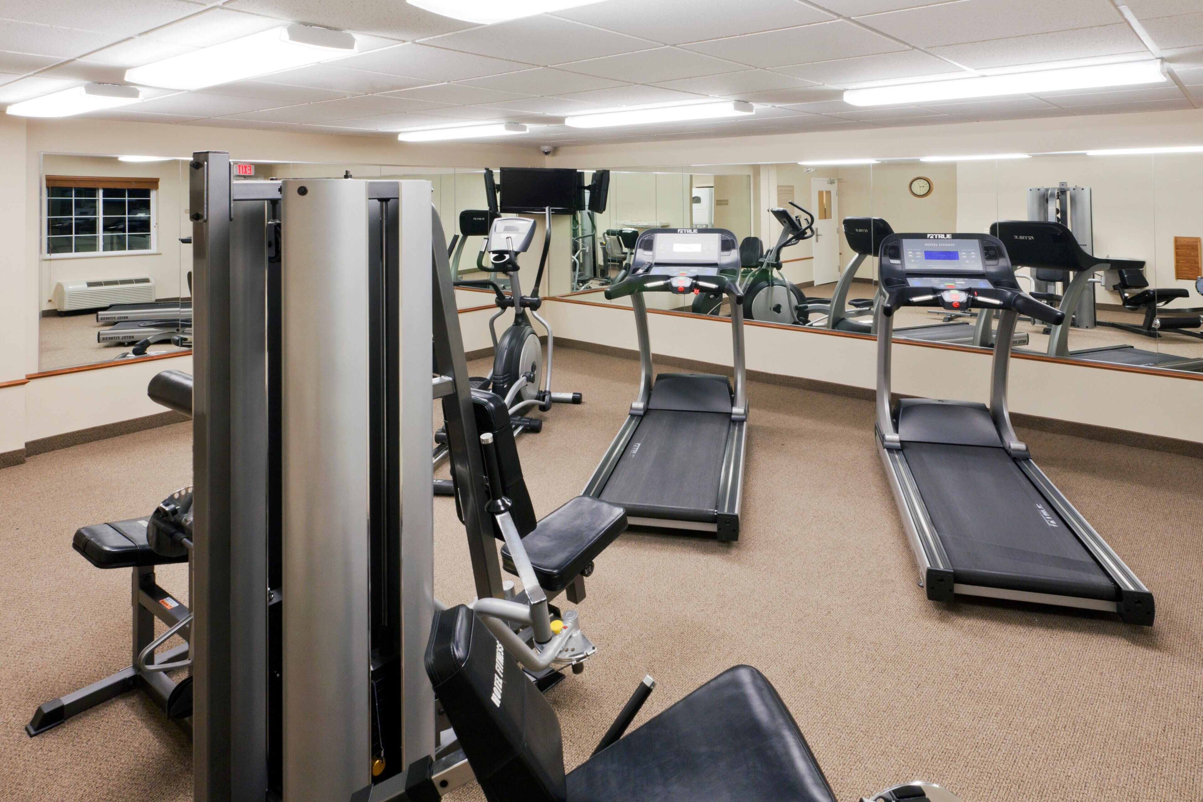 Une salle de sport équipée de tapis de course, de vélos d’exercice et d’appareils de musculation.