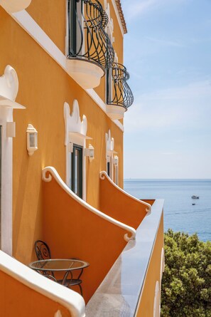 A balcony with a glass table and chairs, overlooking a body of water. - Hotel Savoia (Positano)