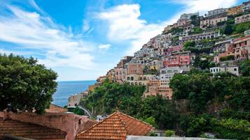 A coastal town with terracotta-roofed buildings, steep hillside architecture, and a view of the sea.