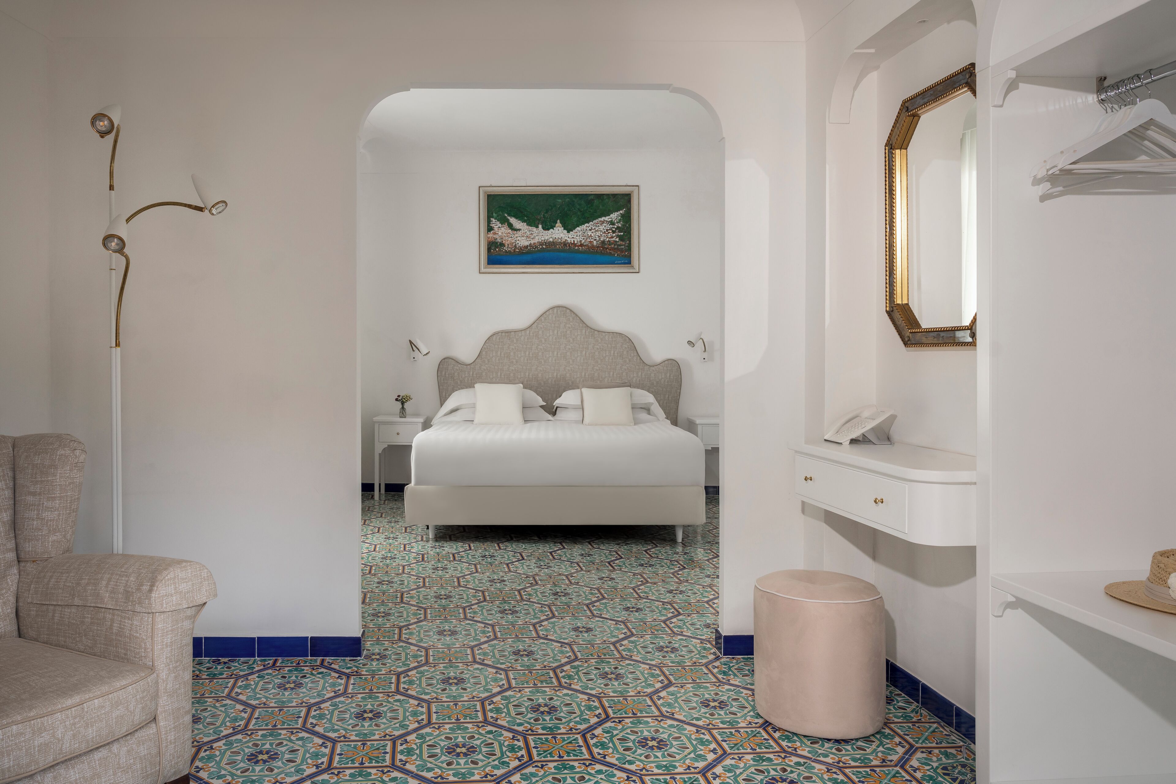 A bedroom with a bed, a nightstand, a mirror, and a wall-mounted picture.