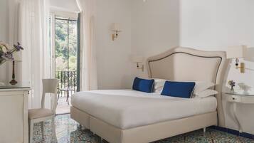 Quarto com cama, cadeira, escrivaninha e varanda com vista.