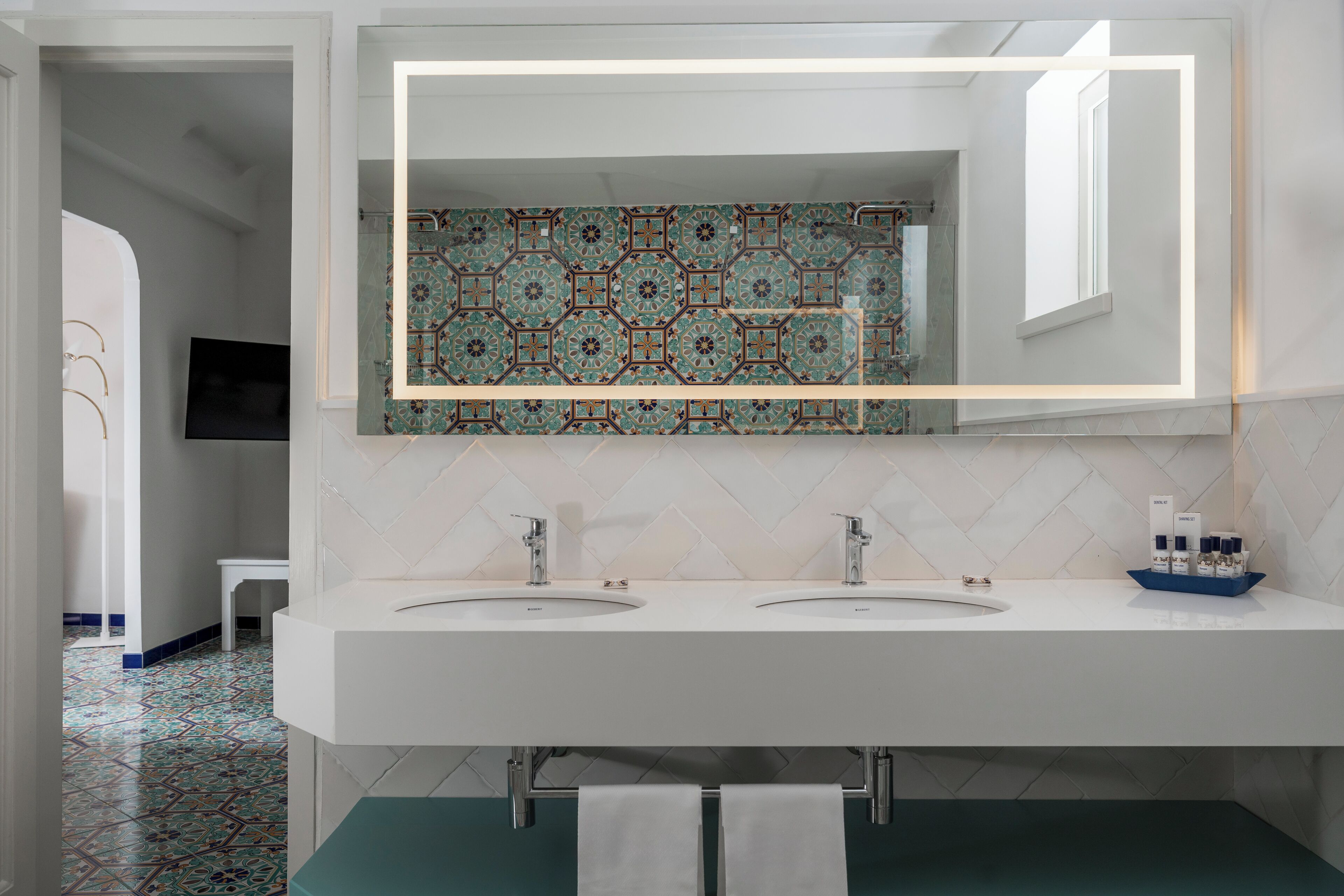 Un baño moderno con dos lavamanos, un espejo grande y un salpicadero de azulejos estampados.