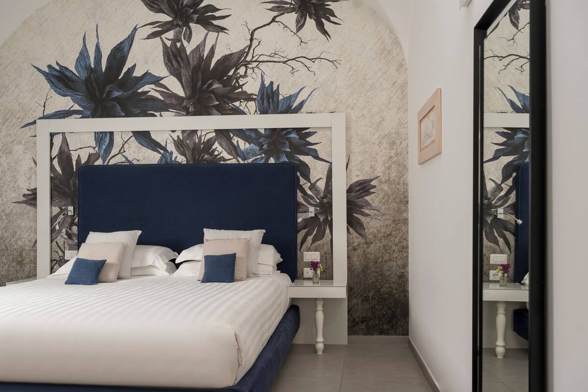 Une chambre à coucher avec un grand lit, une table de chevet et un miroir.