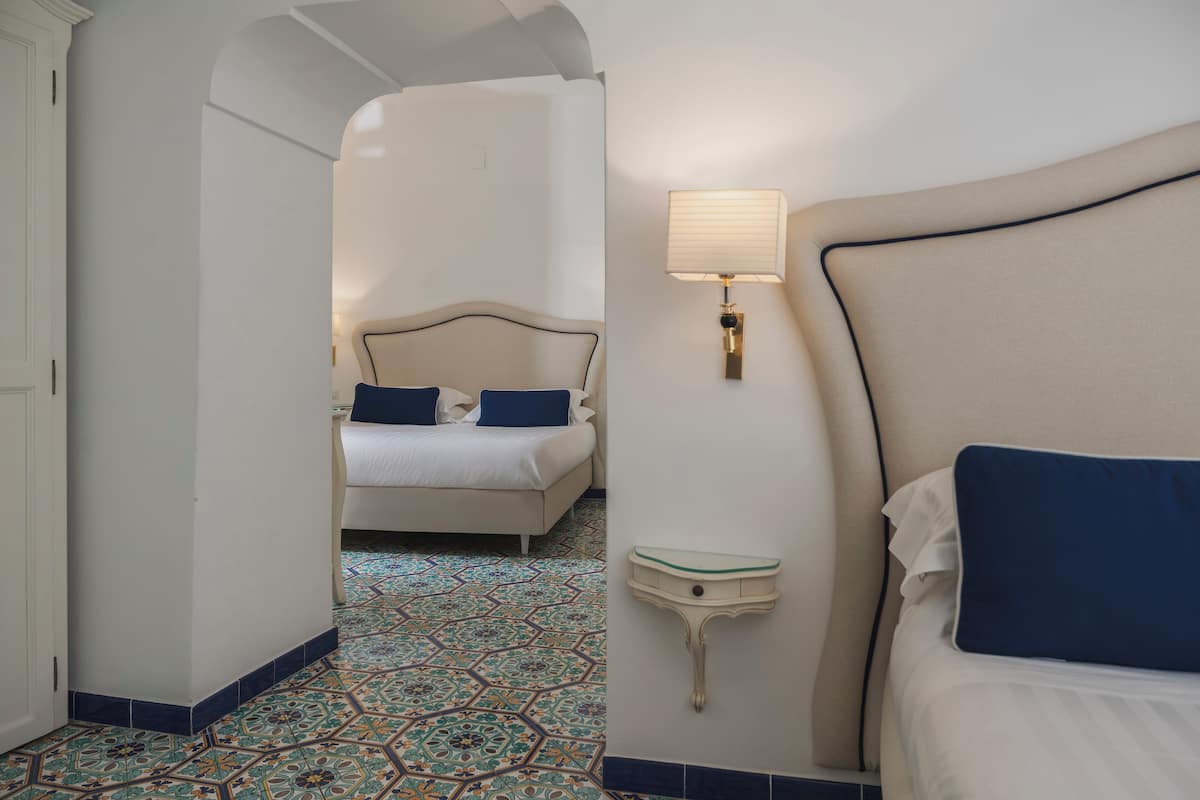 Une chambre d’hôtel avec un lit, une table de chevet, une lampe et un sol à motifs.
