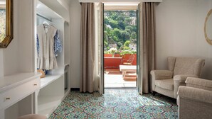 Una habitación con suelo estampado, una zona de estar con una silla, un armario y vistas a un balcón con plantas.