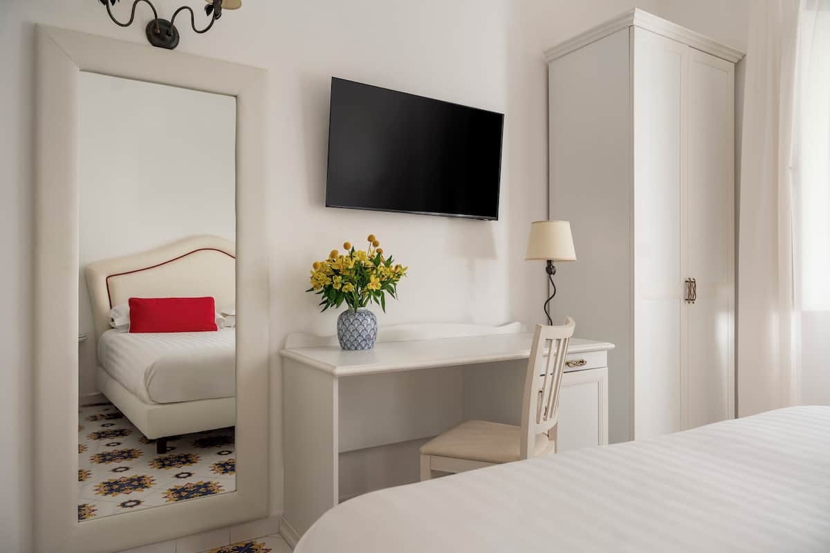 Une chambre d’hôtel avec un lit, un bureau et une chaise, une télévision et une lampe.