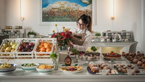 Un bufé con diversas frutas, pasteles y una pieza decorativa central.