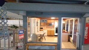 A small, enclosed commercial space with a sign indicating a pool closure. Inside, there is a kitchen area with a microwave, sink, and cabinets. - Mountain View Motel (Bishop)