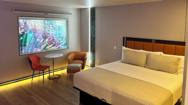 A modern hotel room with a large bed, a small table, a chair, and a wall-mounted TV. - Mountain View Motel (Bishop)