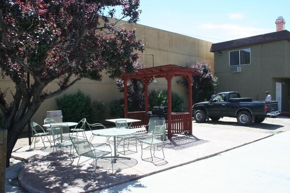 An outdoor patio with tables and chairs, a red pergola, and a parked truck.