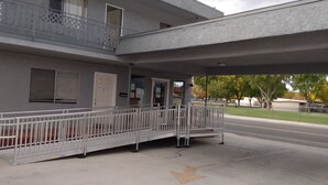 A building with a covered entrance, a metal barrier, and a sign indicating 'OPEN'. - Mountain View Motel (Bishop)