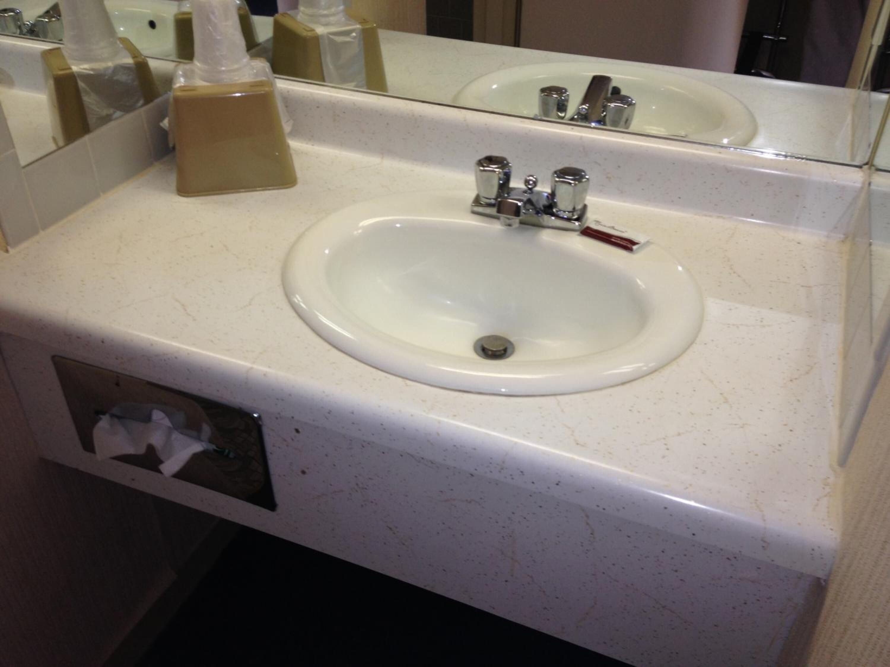 A bathroom sink with a mirror above it, a soap dispenser, and a tissue box.