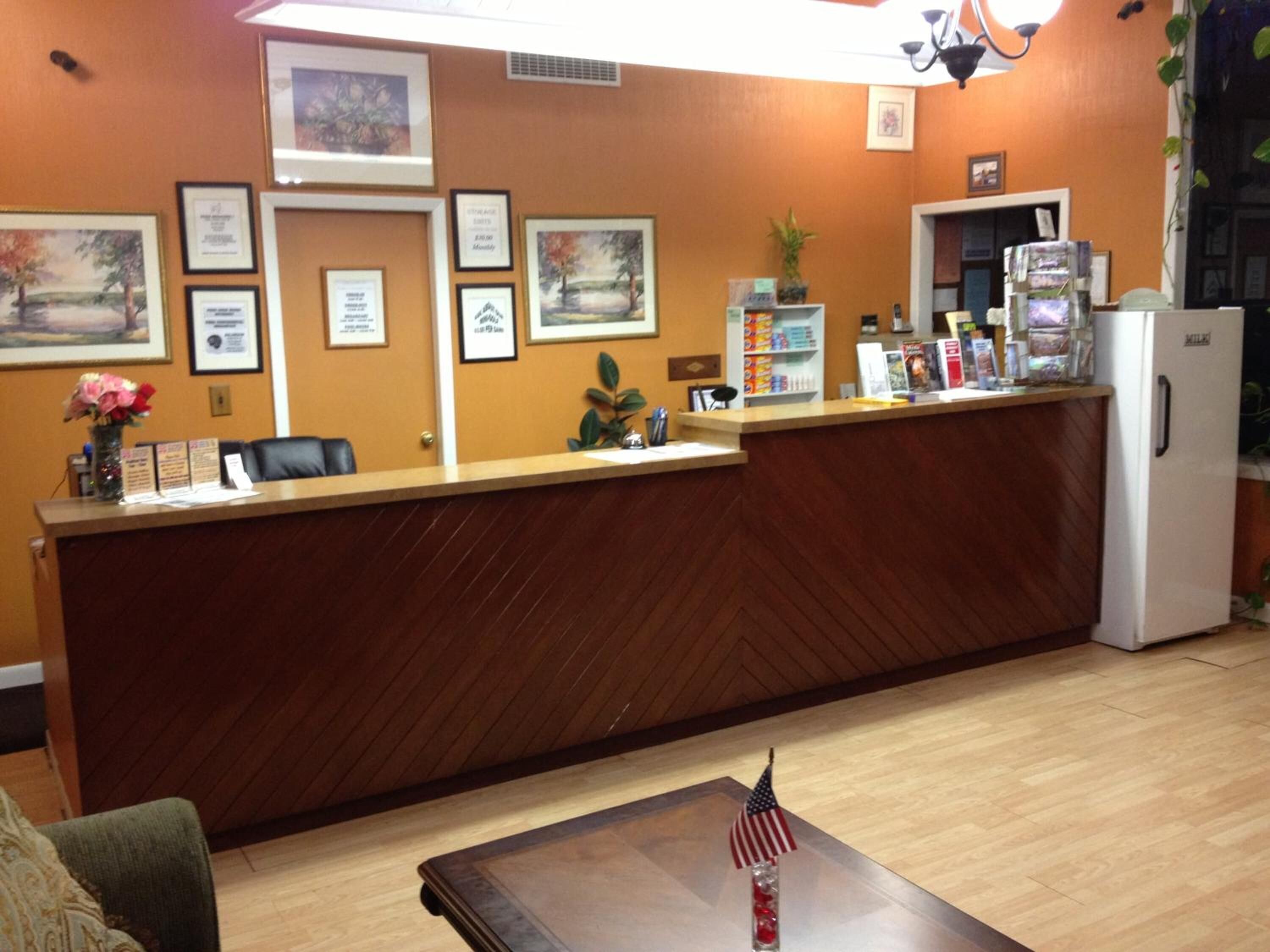 A reception desk with framed certificates, a refrigerator, and a coffee machine.