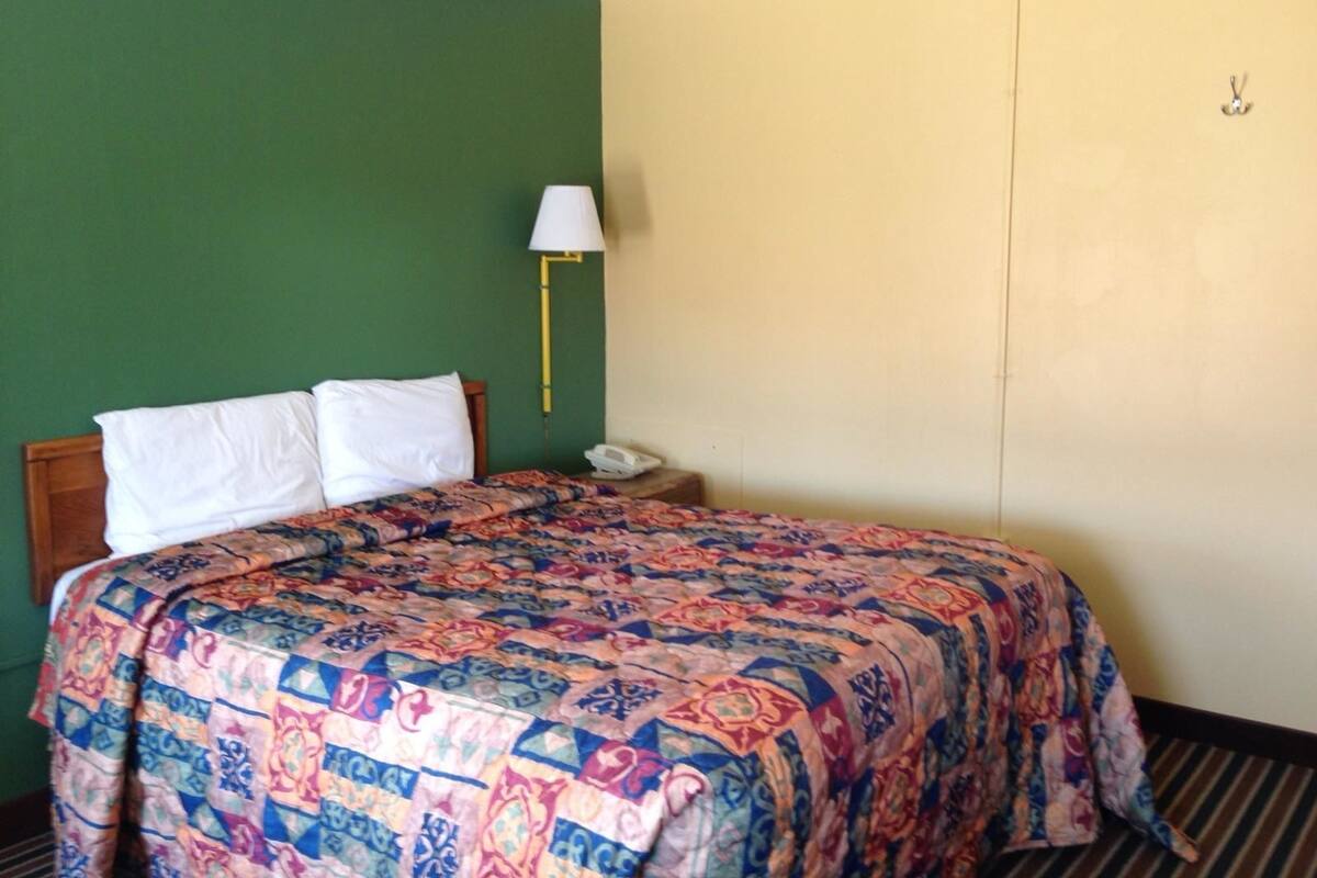Une chambre d’hôtel avec un lit, une table de chevet, une lampe et un téléphone.