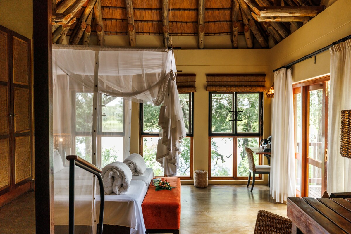 A room with a bed, bench, and a view of the outdoors.