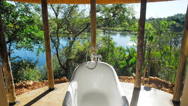 Una bañera con vistas a un lago y árboles.