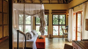 A room with a bed, a bench, a chair, and a dining table. - Divava Okavango Resort & Spa (Divundu)