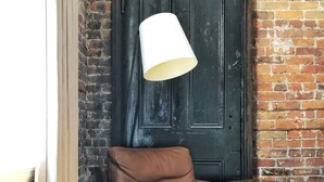 A room with a leather sofa, a table, and a dark wooden door. - Victorian Hotel (Vancouver)