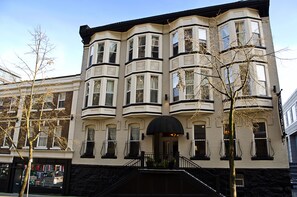 A multi-story building with bay windows and a black awning over the entrance. - Victorian Hotel (Vancouver)