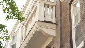 A multi-story building with a classic architectural style, featuring large windows and a balcony with ornate railings. - Victorian Hotel (Vancouver)