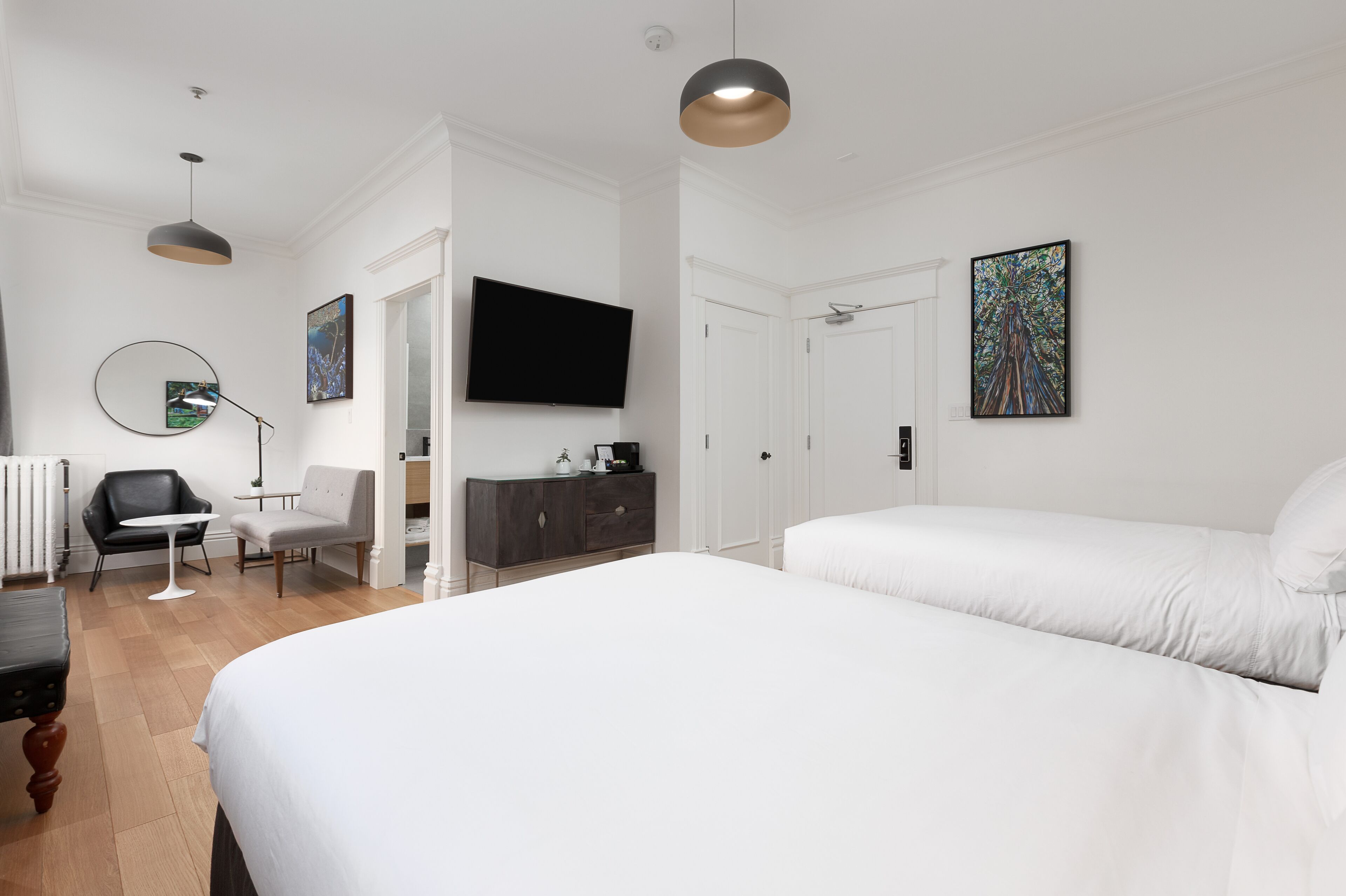 Una camera d'albergo moderna con un letto grande, una TV a schermo piatto, una scrivania con sedia e un comò.
