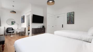 A modern hotel room with a large bed, a flat-screen TV, a desk with a chair, and a dresser.