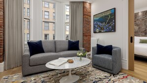A modern living room with a grey sofa, a round coffee table, and a patterned rug. - Victorian Hotel (Vancouver)