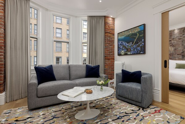 A modern living room with a grey sofa, a round coffee table, and a patterned rug. - Victorian Hotel (Vancouver)