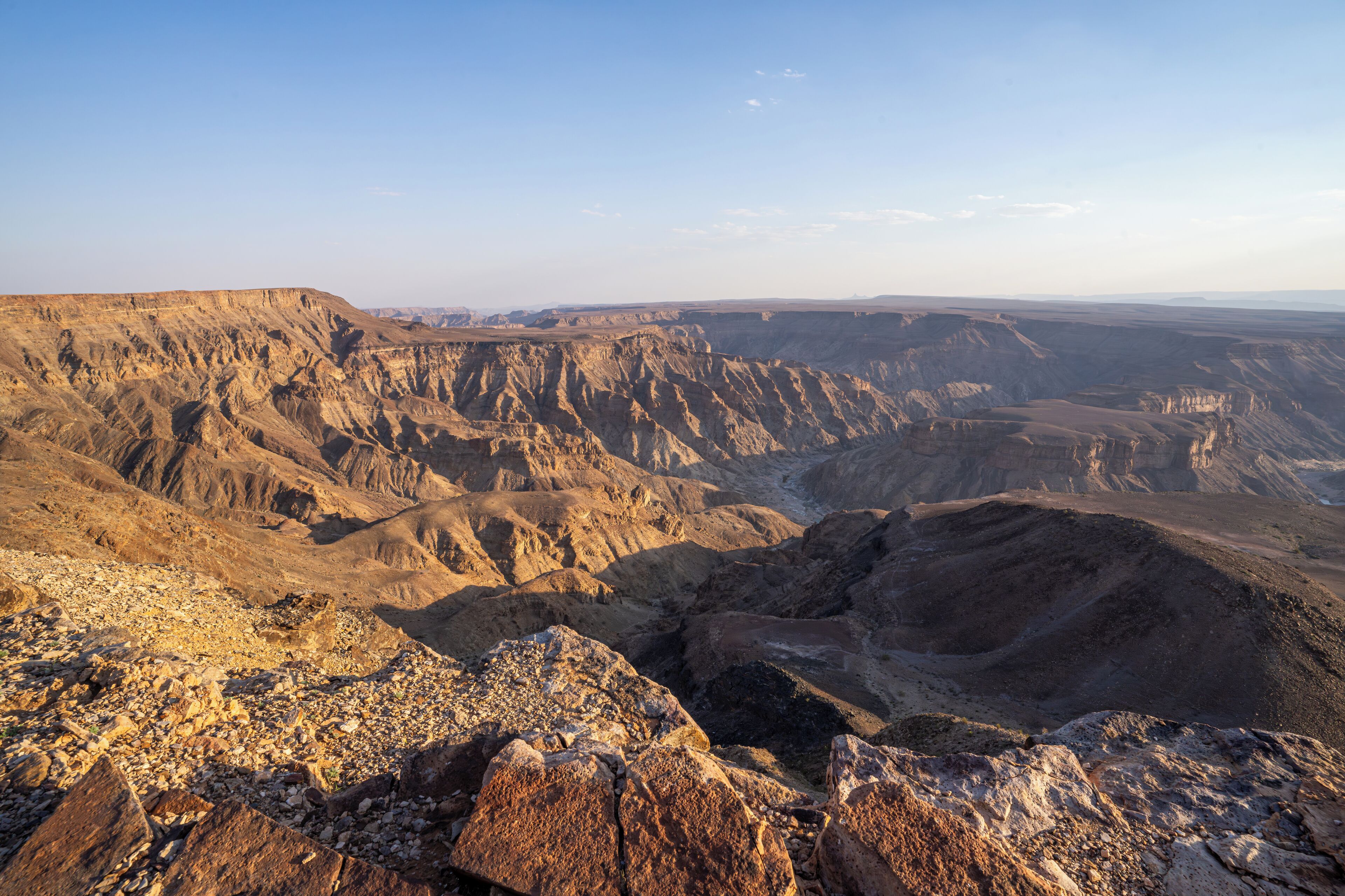 A rugged canyon landscape with rocky terrain and a clear sky.