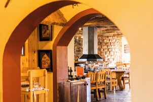 Un interior rústico con mobiliario de madera, paredes de piedra y techo de paja.