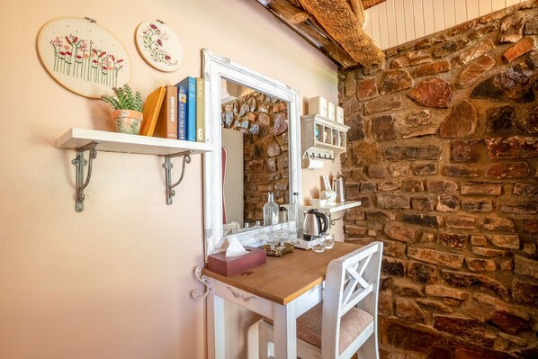 A wooden vanity with a mirror, books, and a potted plant.