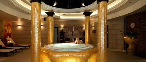 A luxurious lobby with a central hot tub, ornate columns, and a high ceiling.