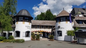 A traditional building with two towers, a central entrance, and a sign reading "Schloss Tavern." - Schlosshotel Rosenegg (Fieberbrunn)