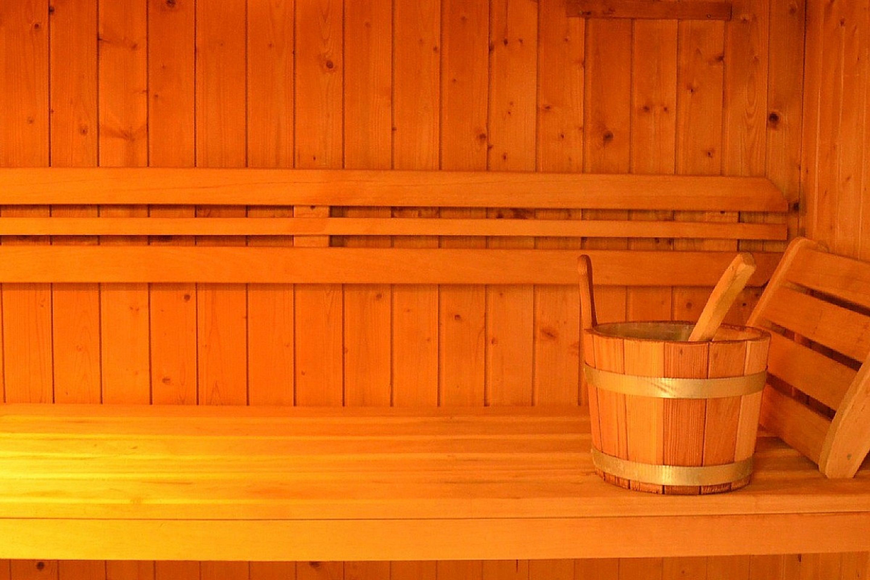 Un sauna en bois avec des bancs et un seau en bois.