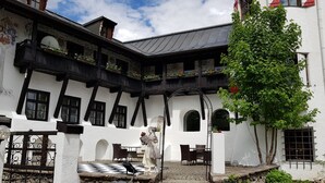 A traditional building with a courtyard, stone steps, and a statue. - Schlosshotel Rosenegg (Fieberbrunn)