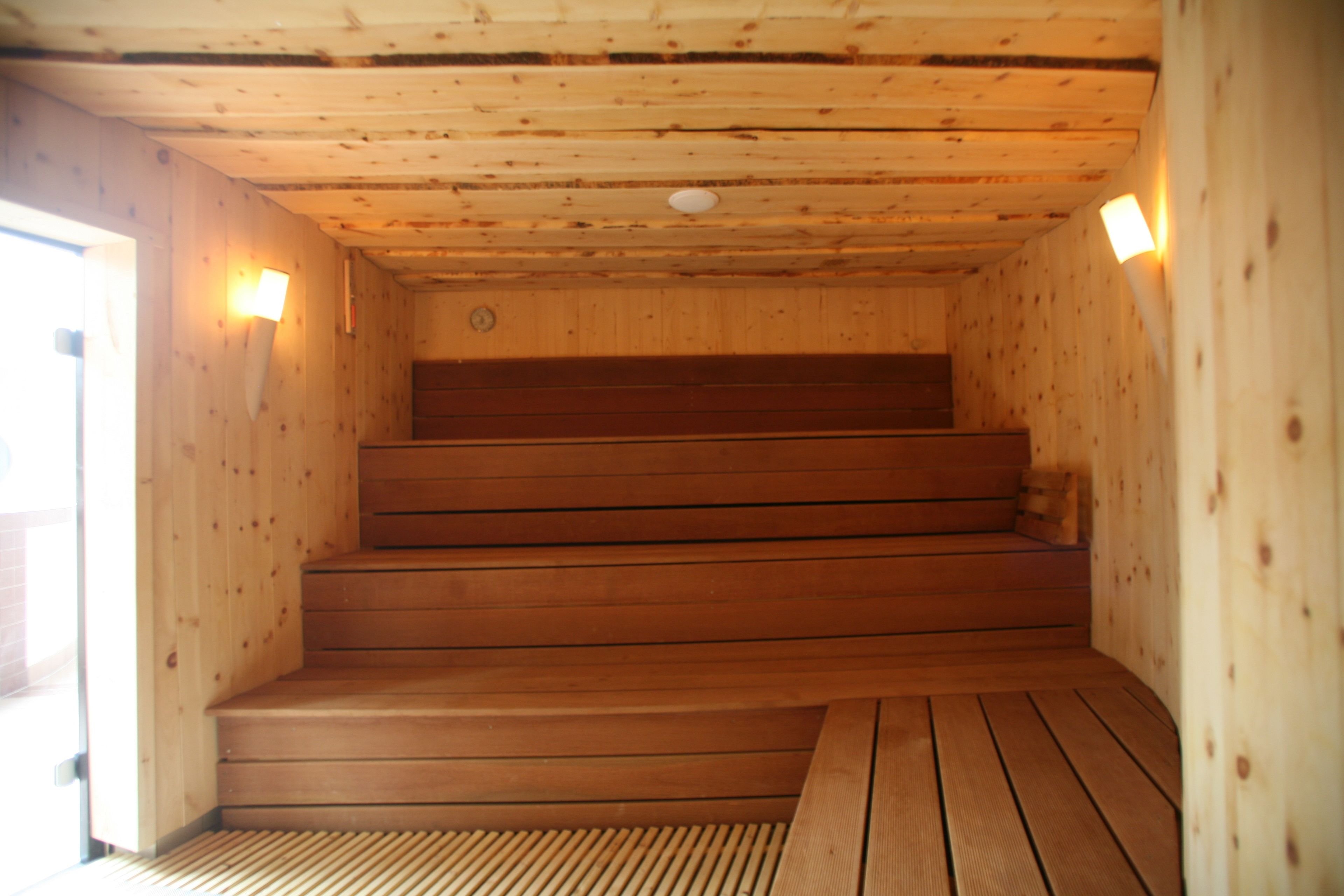 A wooden sauna with a set of wooden steps leading to a bench.