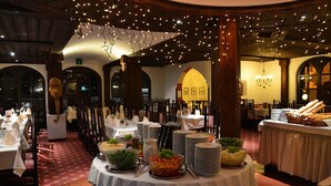 A banquet hall with round tables set for a meal, decorated with white tablecloths and surrounded by chairs. - Schlosshotel Rosenegg (Fieberbrunn)