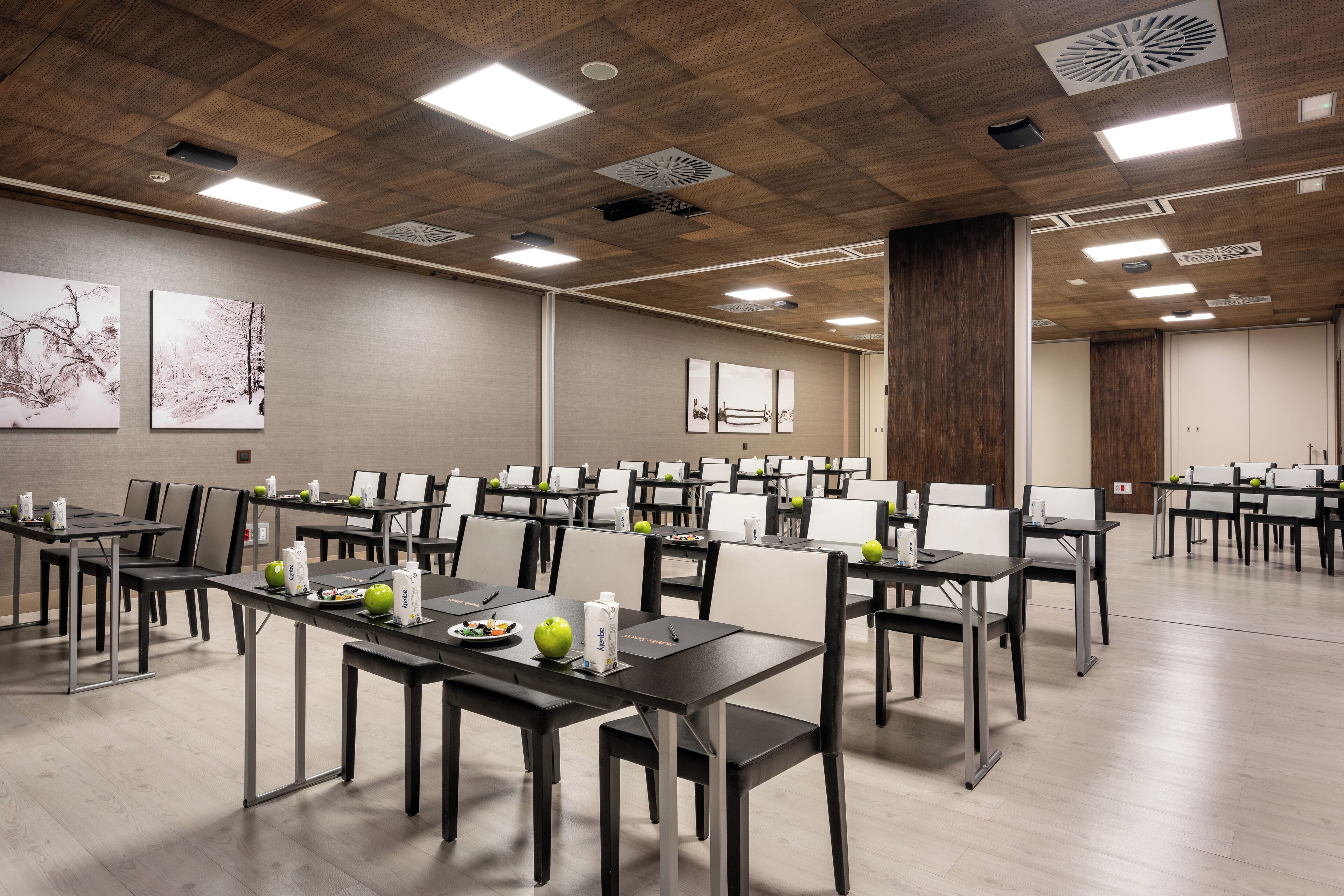 Une salle de conférence dotée de plusieurs tables et de chaises, ainsi que d’ordinateurs portables et de pommes.