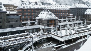 A hotel with multiple buildings, snow-covered roofs, and a central courtyard with trees and seating areas. - Hotel Val De Neu (Naut Aran)