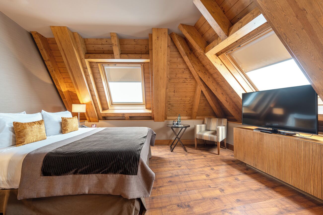 A bedroom with a bed, a TV, a small table, and a chair.