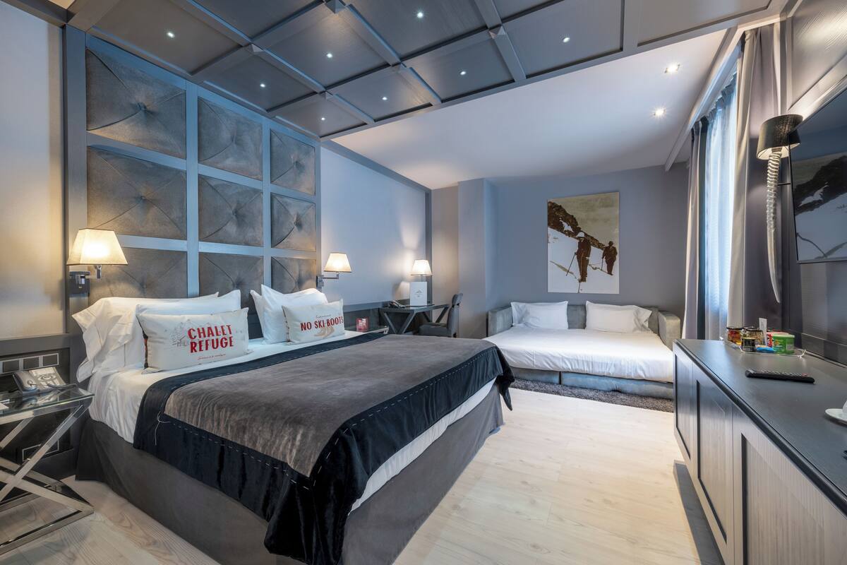 A modern hotel room with two beds, a desk, and a large window.