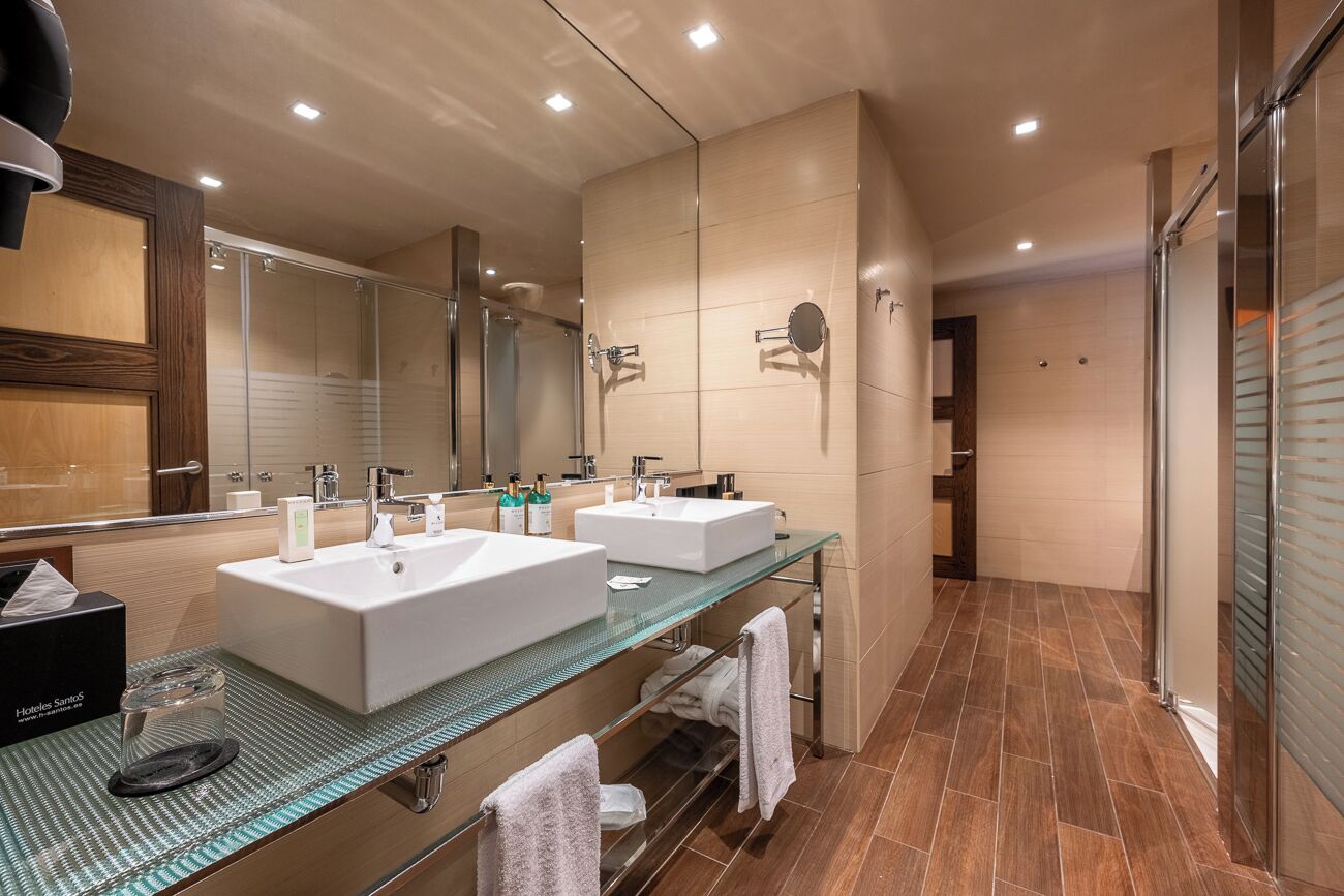 A modern bathroom with two sinks, a glass vanity, and a large mirror.